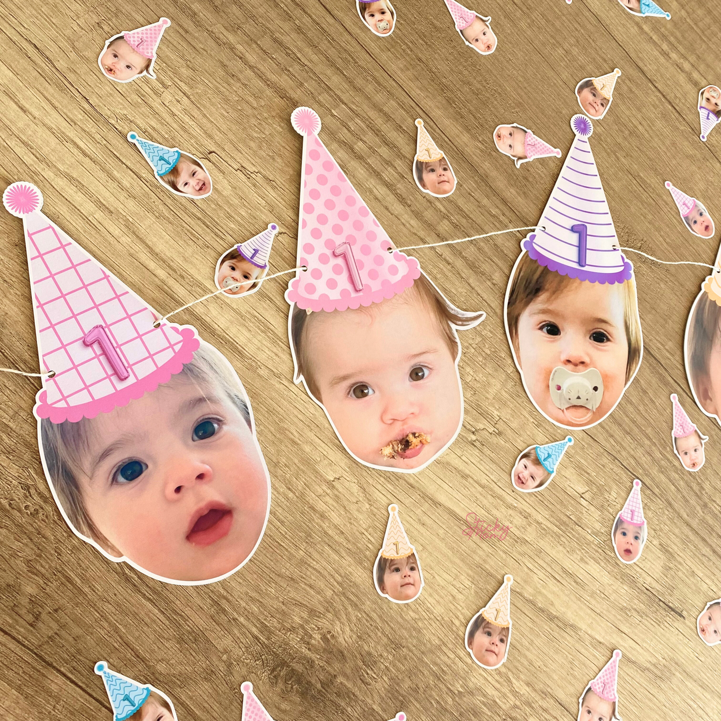 Decorative string with baby faces wearing party hats on a wooden surface
